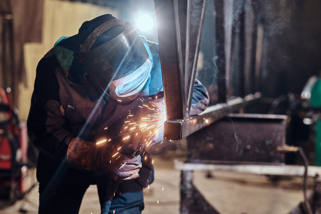 worker welding metal gate of an apartment house